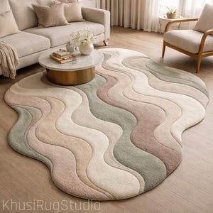 May include: A large, uniquely shaped area rug with a wavy, organic design. The rug features a blend of soft colors, including beige, pink, and green, creating a calming and stylish aesthetic. The rug is placed on a hardwood floor.