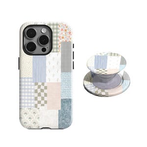 Può includere: Una custodia per telefono e un PopSocket abbinato con un design patchwork. La custodia presenta una varietà di motivi pastello, tra cui sezioni floreali, a quadretti e a righe. Il PopSocket ha un design simile, con una base trasparente.