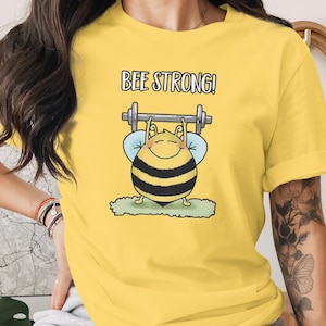 Camiseta con juego de palabras sobre levantamiento de pesas "Bee Strong" - Camiseta divertida para el gimnasio, regalo para amantes del fitness, camiseta de ejercicio con humor