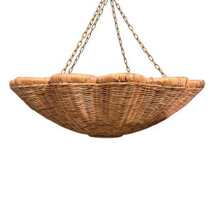 May include: A hanging wicker basket with a scalloped rim, suspended by brass-toned chains. The basket is crafted from light brown wicker and features a broad, shallow bowl design. The chains are connected to the basket's edge, forming a decorative and practical item.