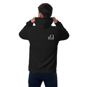 Puede incluir: Sudadera con capucha negra con cordón. La parte trasera de la sudadera con capucha presenta un gráfico blanco de una tecla de teclado con las palabras "Enter and" impresas debajo. La persona de la imagen lleva vaqueros azul oscuro.