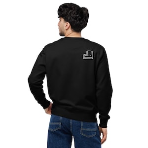 Peut inclure: Sweat-shirt noir avec un motif blanc d'une touche "Entrée" au dos. Le sweat-shirt à col ras du cou et à manches longues est porté par une personne en jean bleu. Le motif est un simple dessin au trait.