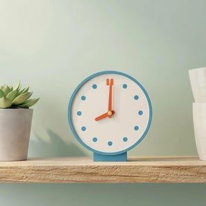 May include: A wooden shelf displays a small succulent in a gray pot, a blue and white clock with orange hands, two white mugs, and a white wire basket with folded gray fabric. The shelf is against a light green wall.