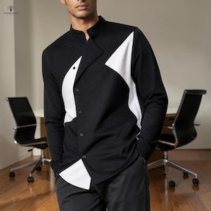 May include: Black long-sleeve shirt with a white geometric design. The shirt has a mandarin collar and button-up front. The shirt is worn with black pants.
