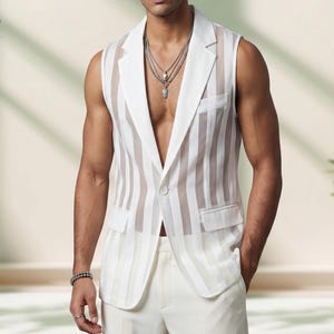 Puede incluir: Un chaleco blanco sin mangas con rayas verticales transparentes. El chaleco tiene solapas con muescas, dos bolsillos delanteros y un cierre de un botón. El modelo también lleva pantalones blancos y collares de plata superpuestos.