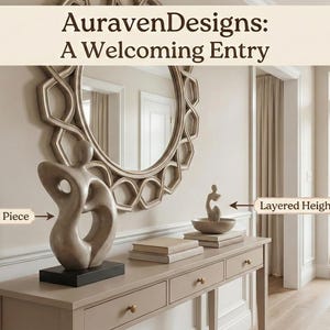 Op de afbeelding: Een uitnodigende entree met een console met decoratieve items, waaronder een sculptuur en boeken. Boven de tafel hangt een grote, sierlijke spiegel. De tekst "AuravenDesigns: A Welcoming Entry" staat bovenaan de afbeelding.