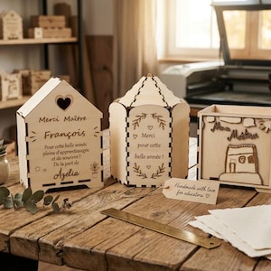 Peut inclure: Plusieurs cadeaux de remerciement pour les enseignants en bois, dont une boîte en forme de maison, une lanterne et une boîte rectangulaire. Sur une table en bois, avec une plante succulente et une bobine de ficelle.