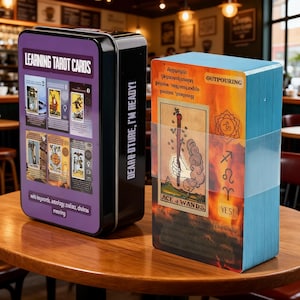 May include: A tarot card set with a black metal tin and a deck of cards. The tin is purple and black with the words "LEARNING TAROT CARDS" and "DEAR FUTURE, I'M READY!" The deck has blue edges and features the "ACE OF WANDS" card.