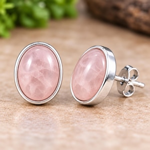 Puede incluir: Un par de pendientes de botón con piedras preciosas de cuarzo rosa pálido, de forma ovalada y superficie lisa, engastadas en biseles de metal pulido de tono plateado. Cada pendiente incluye un cierre de presión estándar.