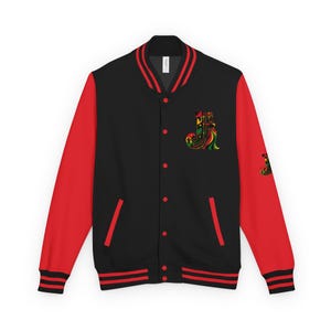 May include: A black varsity jacket with bright red sleeves, a ribbed collar, and cuffs featuring red stripes. The front displays a stylized letter J with green, yellow, and red patterns on the left chest, and a smaller matching J on the right sleeve.