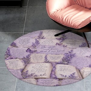 Può includere: Un tappeto rotondo con un design lavanda e bianco. Il tappeto presenta testo scritturale, rametti di lavanda e illustrazioni di farfalle. Il testo centrale recita: "Fermatevi, e sappiate che io sono Dio."