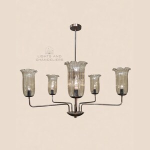 May include: A chandelier with five lights. The lights are encased in bell-shaped, ribbed glass shades. The fixture has a bronze finish and is suspended from a ceiling mount. The text "LIGHTS AND CHANDELIERS" is visible.