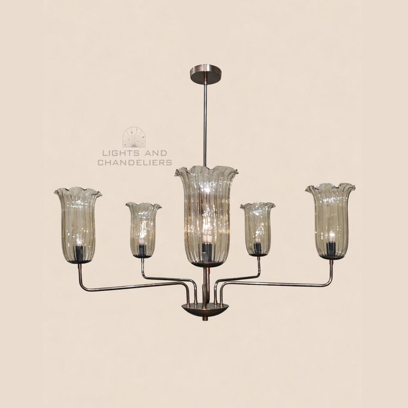 May include: A chandelier with five lights. The lights are encased in bell-shaped, ribbed glass shades. The fixture has a bronze finish and is suspended from a ceiling mount. The text "LIGHTS AND CHANDELIERS" is visible.