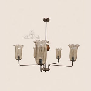 May include: A vintage-style chandelier with five glass shades shaped like flowers. The shades are a light amber color and have vertical ribbed detailing. The fixture has a metal frame and a central wooden accent. The text "LIGHTS AND CHANDELIERS" is visible.