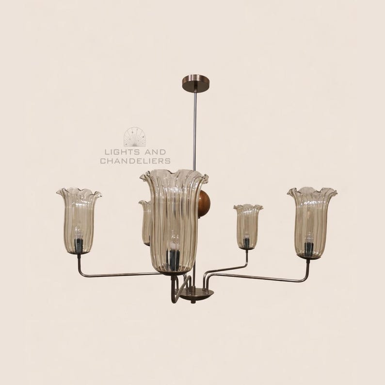 May include: A vintage-style chandelier with five glass shades shaped like flowers. The shades are a light amber color and have vertical ribbed detailing. The fixture has a metal frame and a central wooden accent. The text "LIGHTS AND CHANDELIERS" is visible.