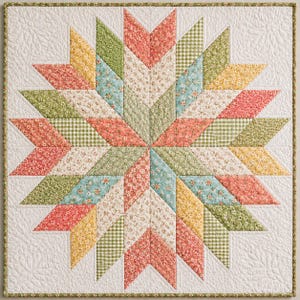 Op de afbeelding: Een vierkante quilt met een centraal sterpatroon bestaande uit ruitvormige stoffen lapjes in tinten koraal, geel, saliegroen en lichtblauw. De stof bevat bloemenprints en vichy-ruitjes, alles geplaatst tegen een witte achtergrond.