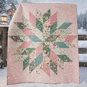 May include: A quilted blanket with a starburst design. The star is composed of floral and solid fabric in shades of pink, green, and blue. The background is a solid light pink, and the blanket has a quilted pattern.