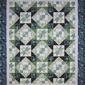 May include: A handmade quilt with a star pattern in shades of green, white, and black. The quilt features a repeating design of stars and squares, with a dark blue floral border. The overall design is symmetrical and visually appealing.