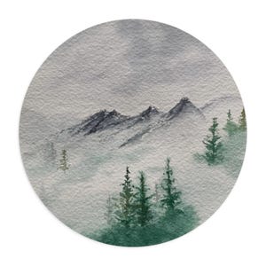 May include: Watercolor painting of a mountain range with evergreen trees in a circular format. The mountains are dark gray, and the trees are green. The background is a light gray, creating a misty effect.
