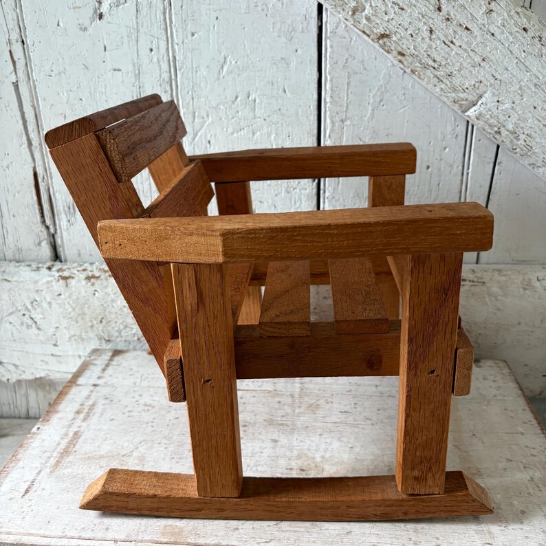 Peut inclure: Petite chaise &agrave; bascule en bois naturel. Le dossier et les accoudoirs sont &agrave; lattes. Le grain du bois est visible. Id&eacute;ale pour un enfant ou une poup&eacute;e. L'arri&egrave;re-plan est blanc.