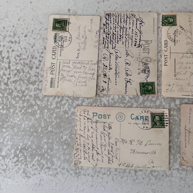 Pode incluir: Quatro postais antigos com mensagens escritas &agrave; m&atilde;o. Os postais s&atilde;o de cor creme com tinta verde e preta. Os postais t&ecirc;m selos do in&iacute;cio do s&eacute;culo XX.