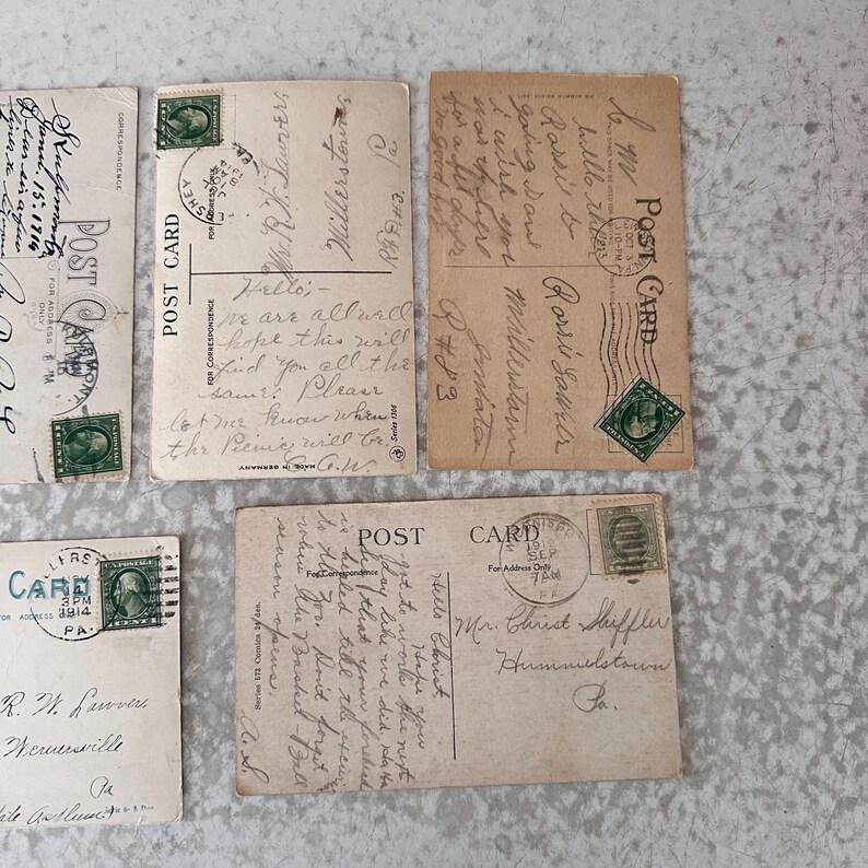 Pode incluir: Quatro postais antigos com mensagens escritas &agrave; m&atilde;o. Os postais s&atilde;o de cores diferentes e t&ecirc;m designs diferentes. Os postais s&atilde;o todos endere&ccedil;ados a pessoas diferentes. Os postais s&atilde;o todos datados de 1914.