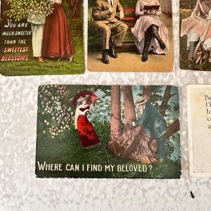 Pode incluir: Postal vintage com um fundo verde e frondoso. Uma mulher com um vestido vermelho segura um guarda-chuva. Um homem de terno est&aacute; subindo em uma &aacute;rvore. O texto "WHERE CAN I FIND MY BELOVED?" est&aacute; impresso na parte inferior.