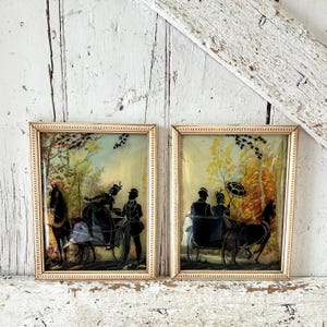 Puede incluir: Dos obras de arte de siluetas vintage enmarcadas. Cada una presenta una silueta negra de un carruaje tirado por caballos con pasajeros y un conductor. Los fondos tienen un paisaje pintado con tonos amarillos, verdes y azules. Los marcos son dorados.