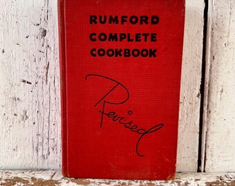 May include: A red hardcover cookbook titled "Rumford Complete Cookbook" with the word "Revised" handwritten in black ink on the front cover.