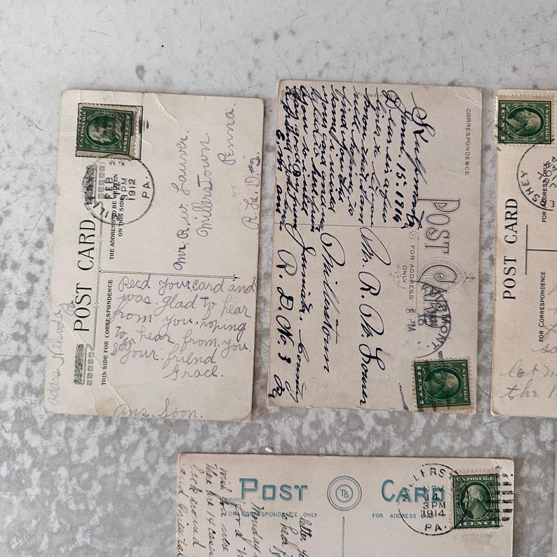 Pode incluir: Quatro postais antigos com mensagens escritas &agrave; m&atilde;o. Os postais s&atilde;o de cor creme com tinta preta e verde. Os postais t&ecirc;m selos de 1912 e 1914.