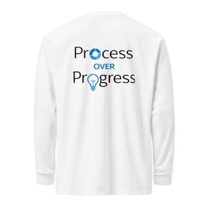 Peut inclure: T-shirt blanc à manches longues avec le texte "Process Over Progress" en noir et bleu. Le mot "Process" est surmonté d'une icône d'engrenage bleue, et "Progress" d'une ampoule bleue.