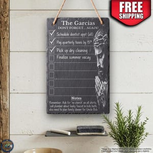 May include: A rectangular slate hanging sign with a rope hanger featuring a checklist titled The Garcias DONT FORGET... AGAIN! It includes tasks like Schedule dentist appt, Pay quarterly taxes, Pick up dry cleaning, and Finalize summer vacay, alongside a detailed illustration of a person with a crown of thorns and hands in prayer.