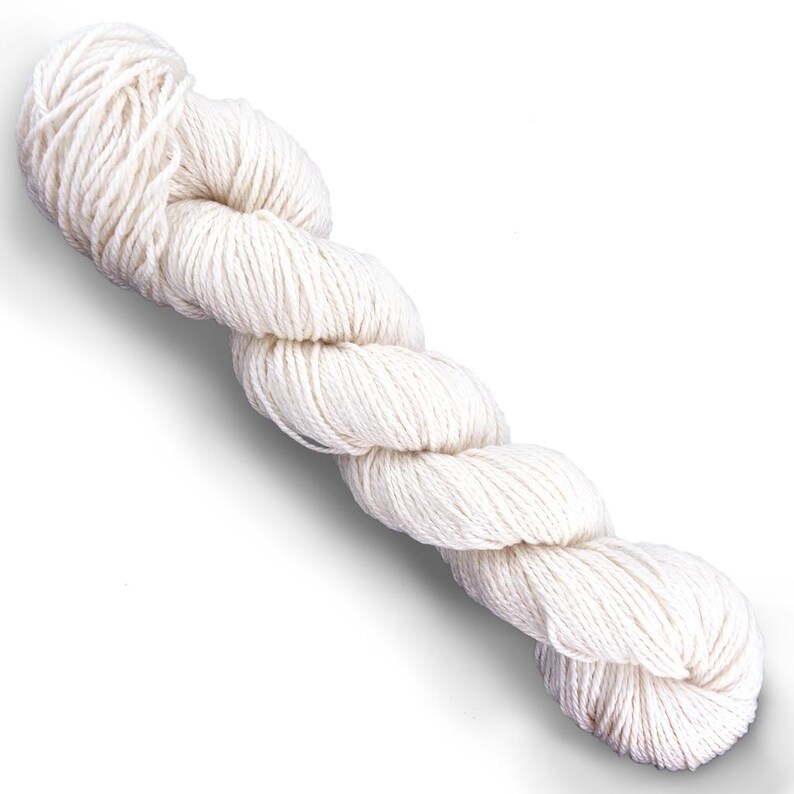 Puede incluir: Una madeja de hilo retorcido de color blanco roto. El hilo est&aacute; compuesto por m&uacute;ltiples cabos, creando una apariencia texturizada y en espiral a lo largo de toda la madeja. El color es un tono crema natural y consistente sin patrones.