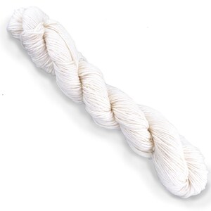 Puede incluir: Una madeja larga y retorcida de hilo color blanco hueso. El hilo est&aacute; compuesto por m&uacute;ltiples cabos, lo que crea una apariencia texturizada similar a una cuerda a lo largo de toda la madeja. El color es un tono blanco crema neutro.