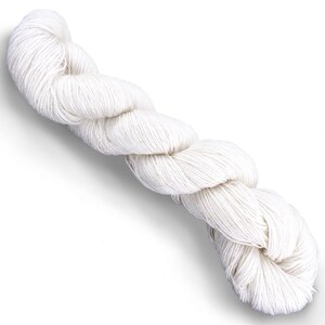 Puede incluir: Una madeja larga y retorcida de hilo color blanco roto. El hilo est&aacute; compuesto por m&uacute;ltiples hebras finas y estrechamente hiladas que crean una apariencia texturizada y continua similar a una cuerda. La madeja est&aacute; dispuesta en diagonal.