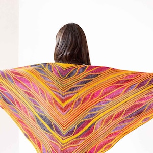 May include: A triangular knit shawl featuring a vibrant, multi-colored pattern of yellow, orange, magenta, and purple yarn. The design consists of intricate, flowing wave-like textures and raised ridges that radiate outward from the center point.