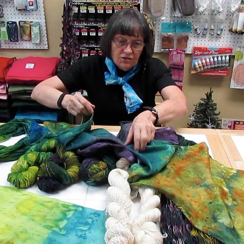 Puede incluir: Una colecci&oacute;n de madejas de hilo y piezas de tela te&ntilde;idas a mano en varios colores, incluyendo verde, amarillo, azul, morado y blanco roto. El surtido incluye manojos de hilo texturizados en verde y morado oscuro junto a muestras de tela.