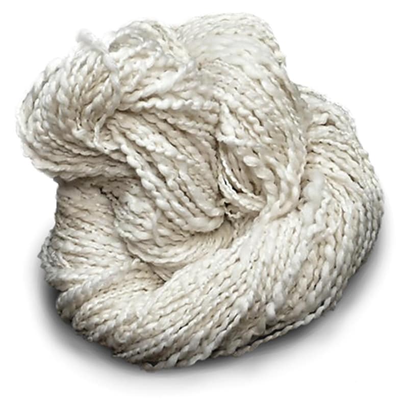 Puede incluir: Una madeja de hilo color blanco roto con una apariencia texturizada y retorcida. El hilo presenta una construcci&oacute;n de m&uacute;ltiples cabos con un ligero brillo, enrollado en un paquete suelto y redondeado que muestra un color crema uniforme.