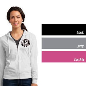 May include: A white zippered hoodie with a black monogram on the left chest. The hoodie is available in black, grey, and fuchsia.