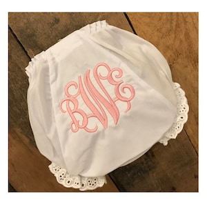 May include: White cotton baby bloomers with a pink embroidered monogram "B.L.L." and white lace trim.