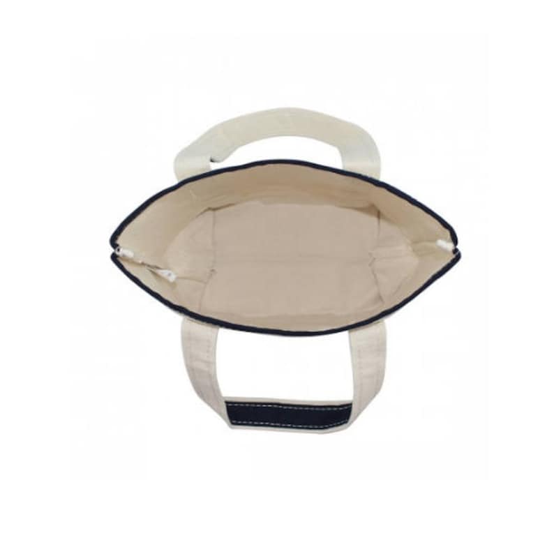 May include: A white canvas tote bag with navy blue trim and handles. The bag is empty and the inside is visible.