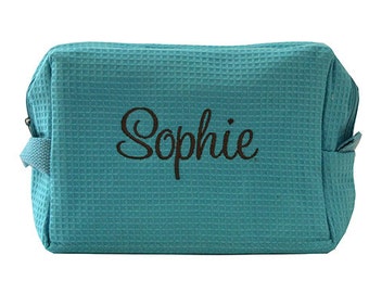 May include: A turquoise blue waffle-textured cosmetic bag with the name "Sophie" embroidered in black.