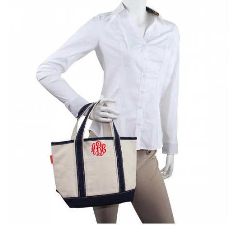 May include: A white canvas tote bag with navy blue trim and a red monogram "RBE".
