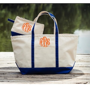 May include: A large white canvas tote bag with blue trim and a smaller white canvas zippered pouch. Both bags feature a monogram in orange.