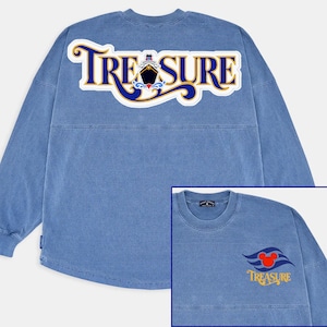 Puede incluir: Una camiseta azul de manga larga con la palabra "TREASURE" en un diseño blanco, dorado y azul en la espalda. El diseño incluye una ilustración de un barco. Una imagen más pequeña muestra la parte delantera de la camiseta con el logotipo de Mickey Mouse y la palabra "TREASURE".