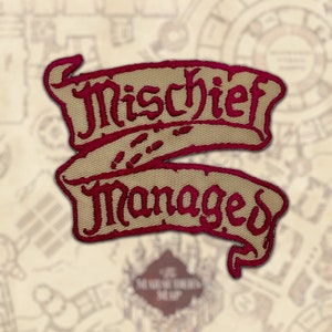 Peut inclure: &Eacute;cusson brod&eacute; avec les mots "Mischief Managed" en fil bordeaux sur une banni&egrave;re beige. Le patch pr&eacute;sente un design de parchemin avec un fond en forme de carte.