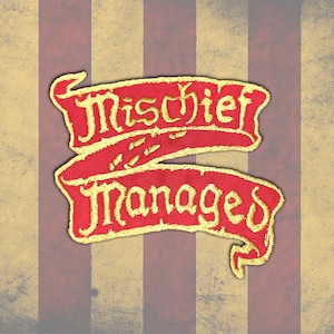 Peut inclure: Un &eacute;cusson rouge brod&eacute; avec les mots "Mischief Managed" en lettres dor&eacute;es. L'&eacute;cusson a la forme de deux banni&egrave;res superpos&eacute;es. Le fond a un aspect vintage avec des rayures verticales rouges et beiges.