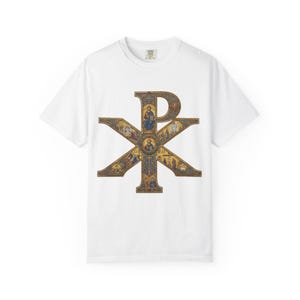 Może przedstawiać: Biały t-shirt z krótkim rękawem z dużym symbolem Chi Rho nadrukowanym z przodu. Symbol jest wypełniony złożonymi, kolorowymi obrazami religijnymi w stylu mozaiki, przedstawiającymi postacie i sceny w odcieniach złota, błękitu i czerwieni.