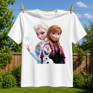 May include: A white short-sleeved t-shirt featuring a graphic print of the characters Elsa, Anna, and Olaf from the movie Frozen. Elsa is on the left with blonde hair, Anna is on the right with braided auburn hair, and Olaf is centered below.