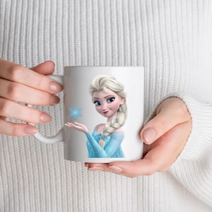 May include: A white ceramic mug featuring a printed graphic of a blonde character with a long braided hairstyle, wearing a light blue dress, and holding a small blue snowflake icon in an outstretched hand against a plain white background.